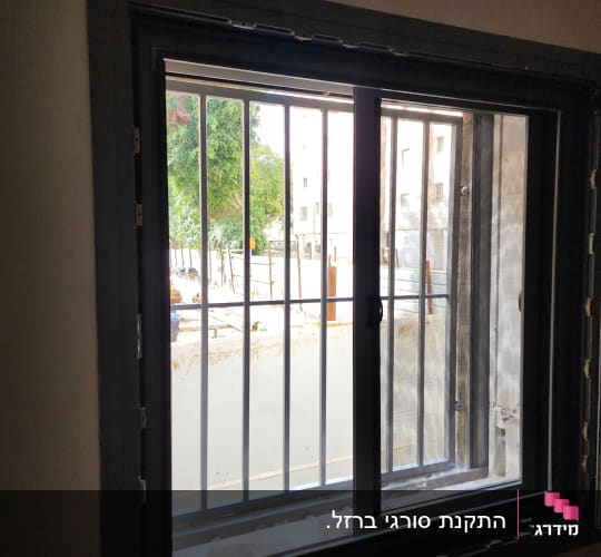 חלון עם מסגרת מתכת וסורגים חיצוניים